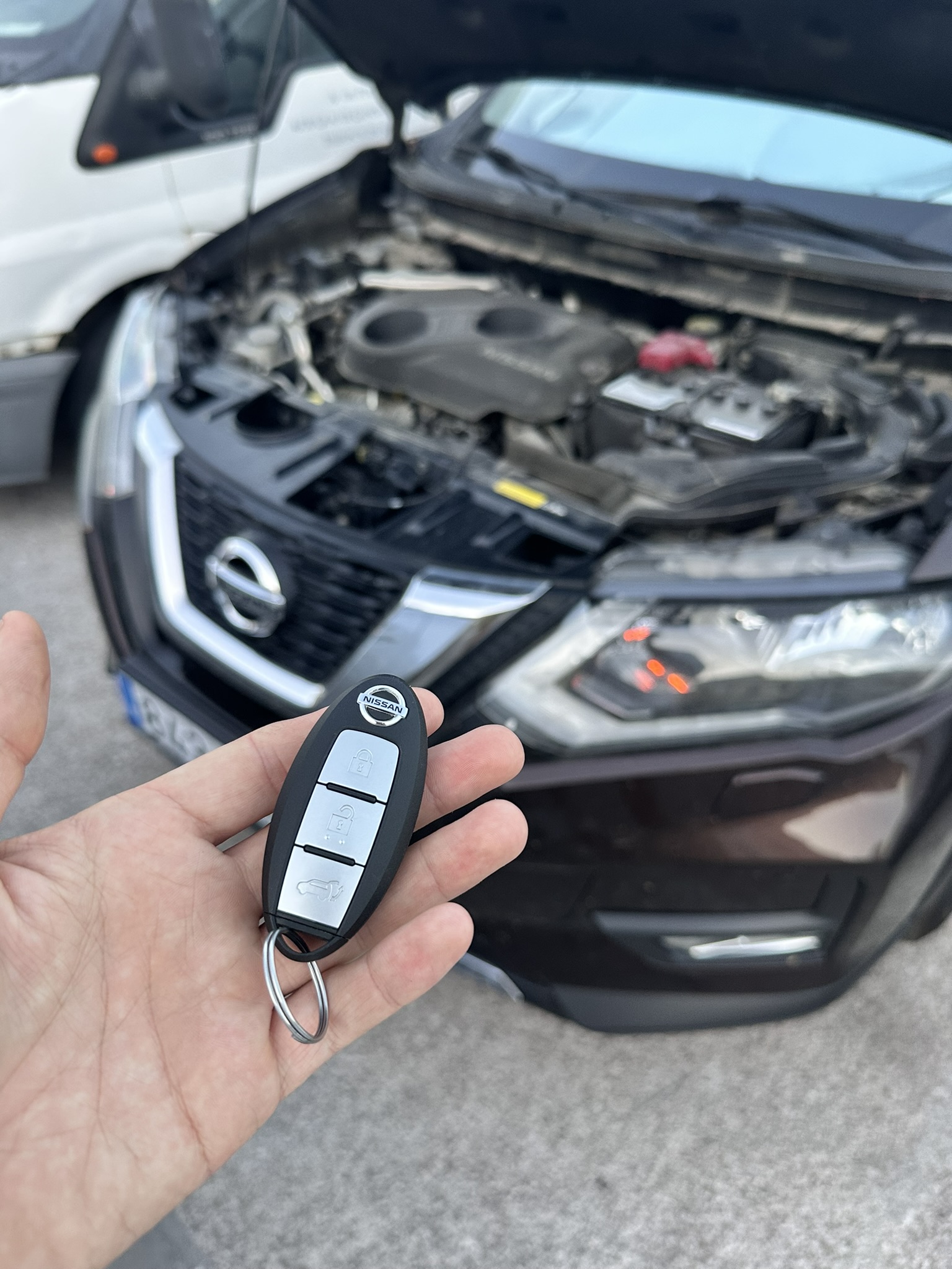 Llave Nissan nueva con coche al fondo